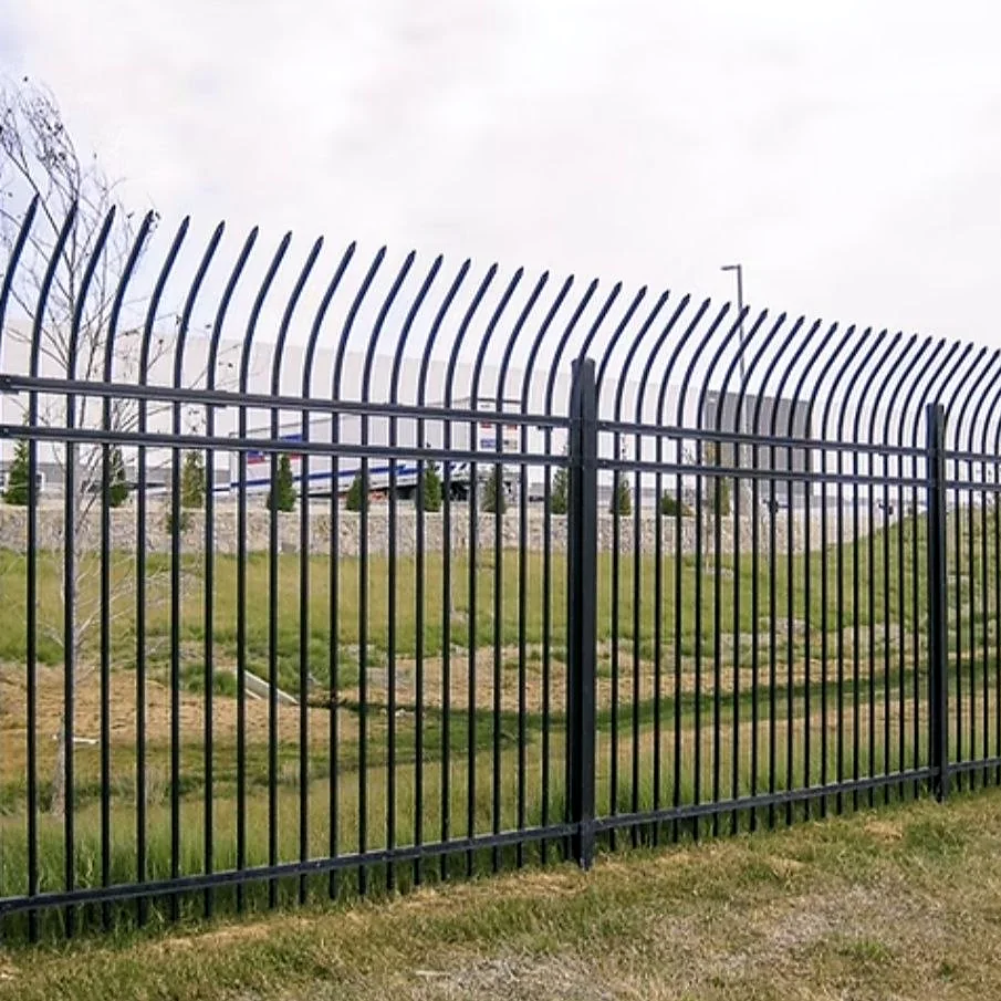 Black steel picket fence with curved spear-top pickets, horizontal rails and square posts, running along a grassy verge.