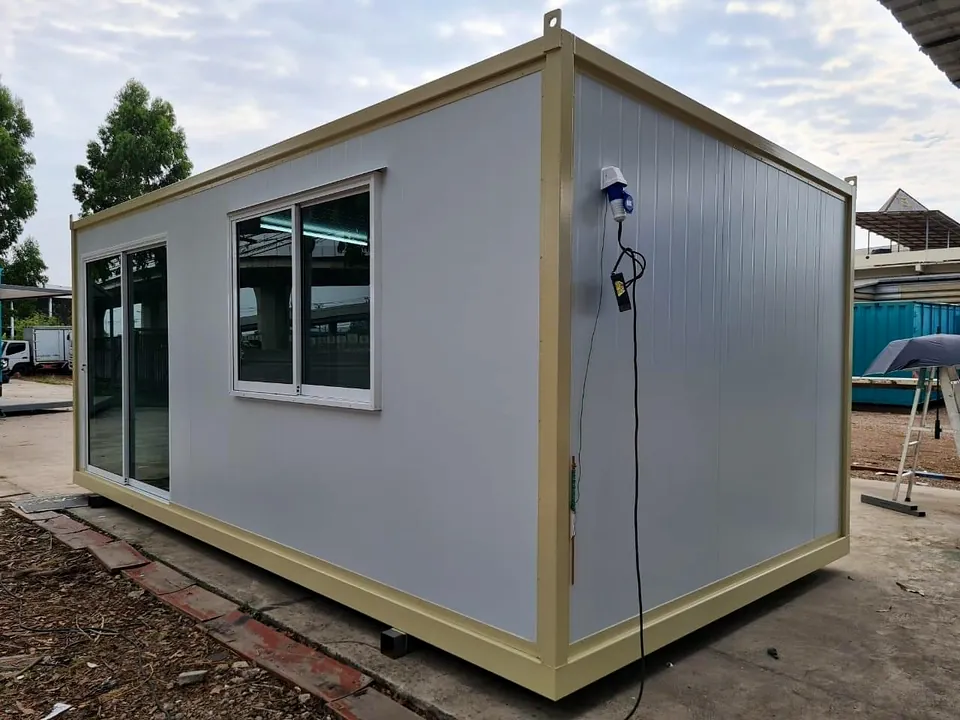 Grey portable cabin with cream frame, glass sliding door and window, with a power lead on the side.